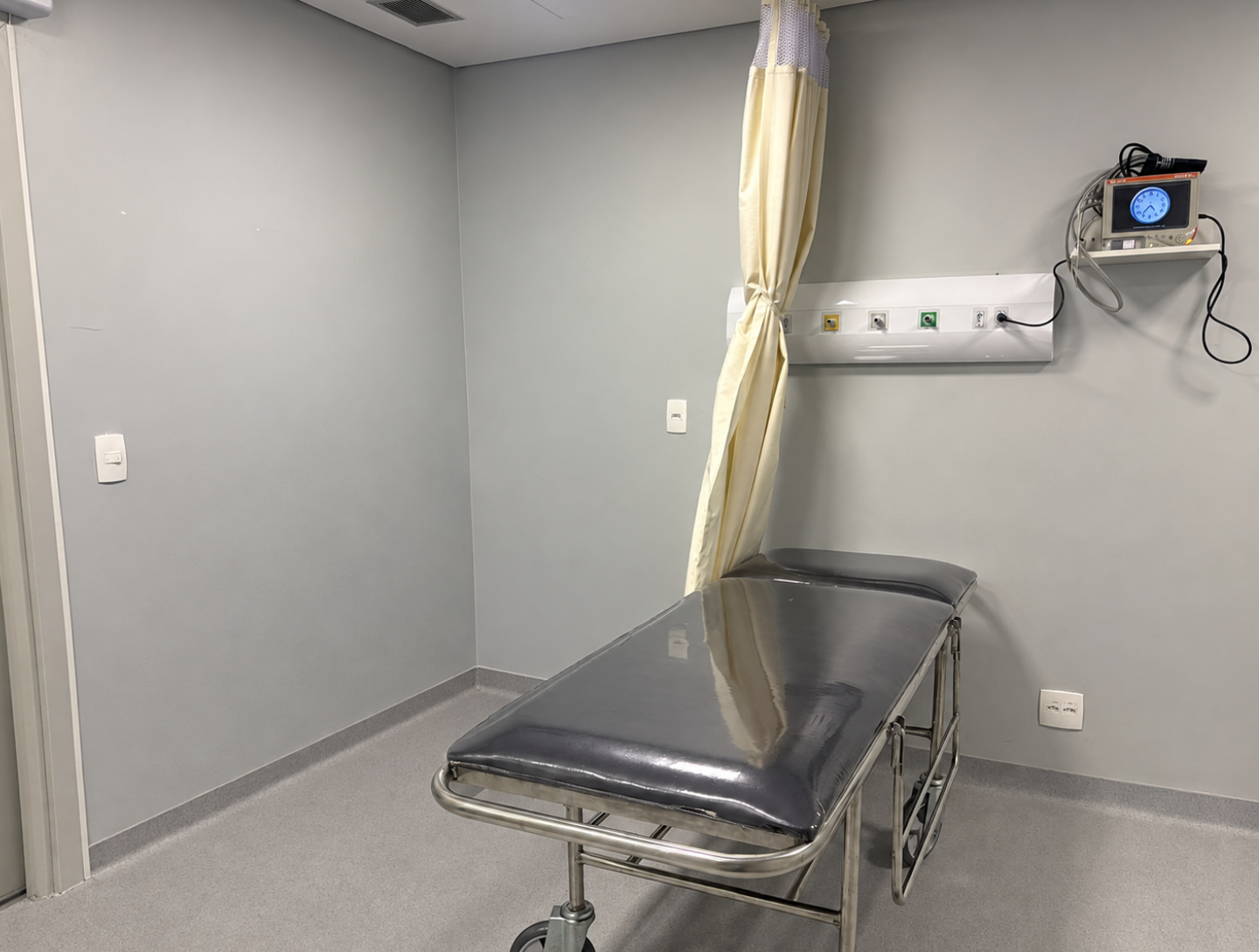 Sala de recuperação pós-operatória com maca e monitor